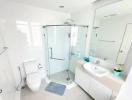 Modern white bathroom with glass shower enclosure and ample natural light