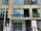 Three-story residential building with balconies and blue window accents