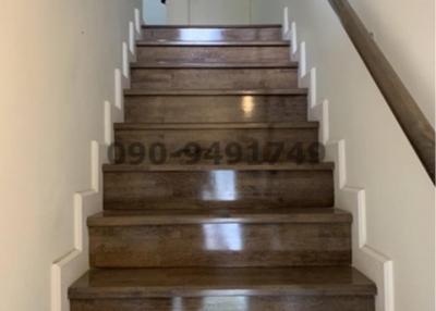 Wooden staircase with white walls leading to an upper floor