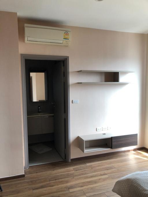 Modern bedroom with an open door leading to a bathroom and air conditioning unit