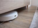 Smart vacuum cleaning under wooden cabinet in modern living space