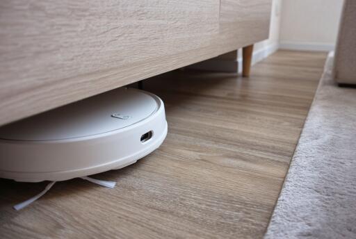 Smart vacuum cleaning under wooden cabinet in modern living space