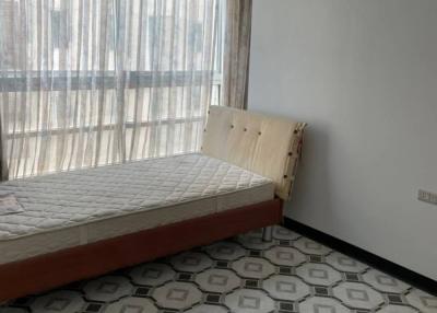 Minimalist bedroom with a single bed and patterned tile flooring