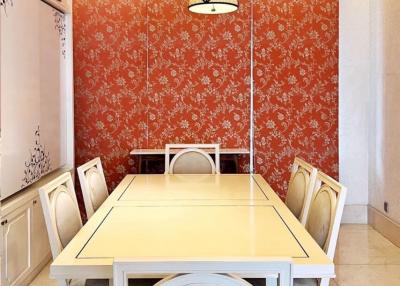 Bright dining room with a large table and orange floral wallpaper
