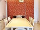 Bright dining room with a large table and orange floral wallpaper