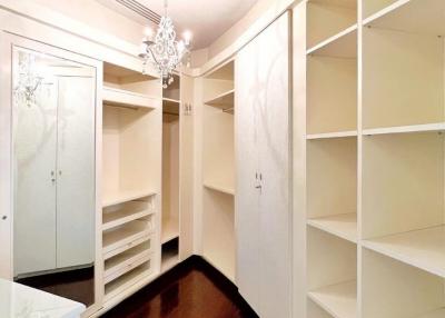 Spacious walk-in closet with built-in shelves and hardwood floors