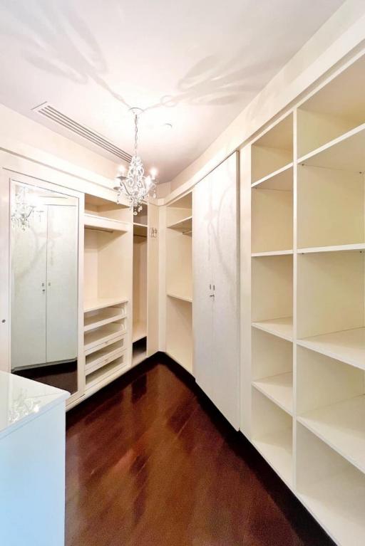 Spacious walk-in closet with built-in shelves and hardwood floors