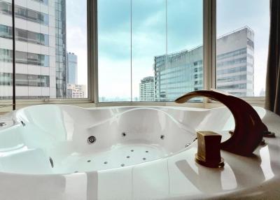 Luxurious bathroom with a large Jacuzzi tub and city view through floor-to-ceiling windows