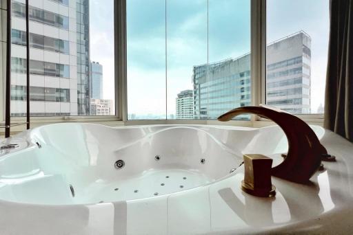 Luxurious bathroom with a large Jacuzzi tub and city view through floor-to-ceiling windows