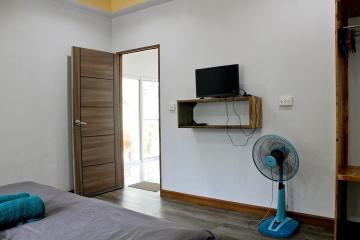 Modern bedroom with wooden door, wall-mounted TV, and large window