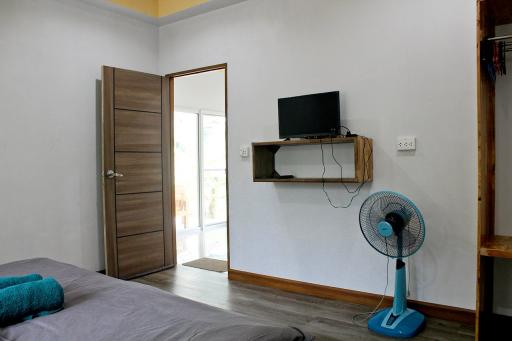 Modern bedroom with wooden door, wall-mounted TV, and large window