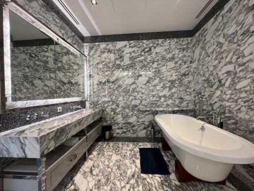 Luxurious bathroom with marble walls and flooring, featuring a freestanding bathtub