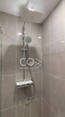 Modern shower with adjustable head and large wall-mounted overhead shower in a tiled bathroom