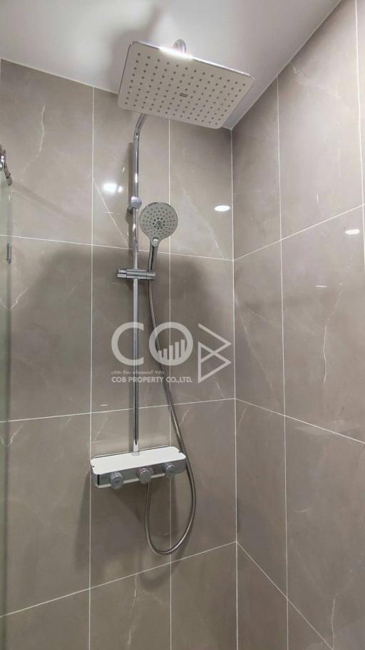 Modern shower with adjustable head and large wall-mounted overhead shower in a tiled bathroom