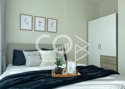 Modern bedroom interior with neutral tones, decorative artwork, and cozy furnishings