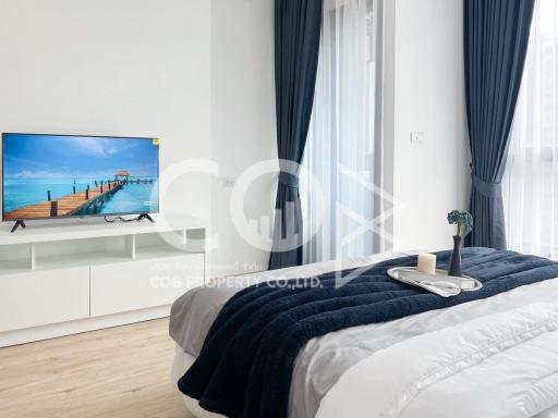 Modern bedroom with a large bed, mounted television, and balcony access