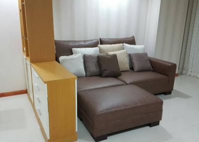 Modern living room with L-shaped brown sofa and white curtains