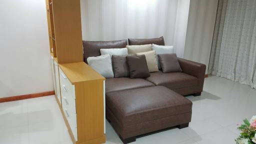 Modern living room with L-shaped brown sofa and white curtains