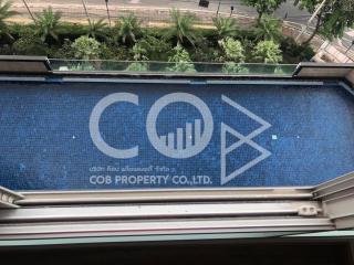 Aerial view of a swimming pool with COB Property Co. Ltd. logo, surrounded by urban scenery