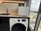 Compact laundry area with modern washing machine and city view