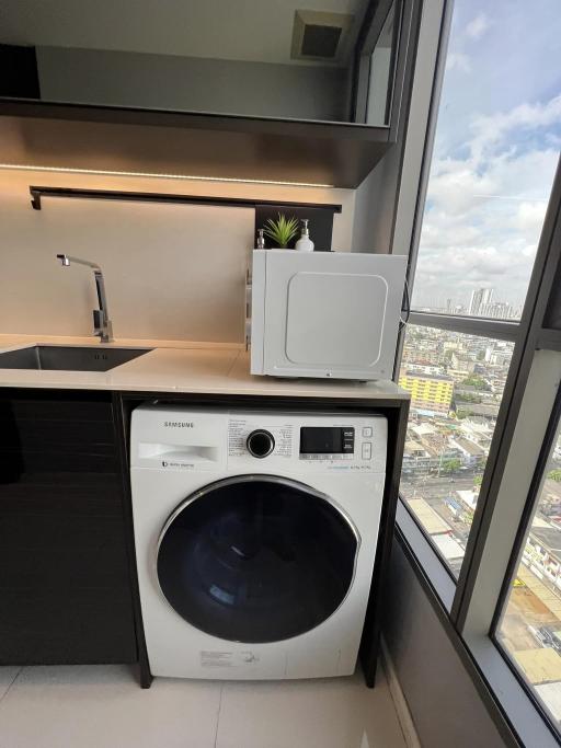 Compact laundry area with modern washing machine and city view