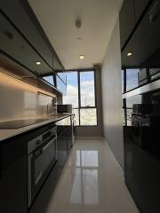 Modern kitchen with sleek black cabinets, large windows, and high-end appliances