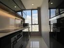 Modern kitchen with sleek black cabinets, large windows, and high-end appliances