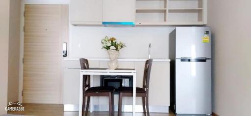 Compact kitchen with dining area including modern appliances and wooden door