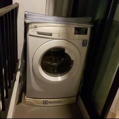 Modern Electrolux washing machine in a compact home laundry area