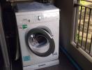 Front-loading Siemens washing machine in a utility area with air conditioner above