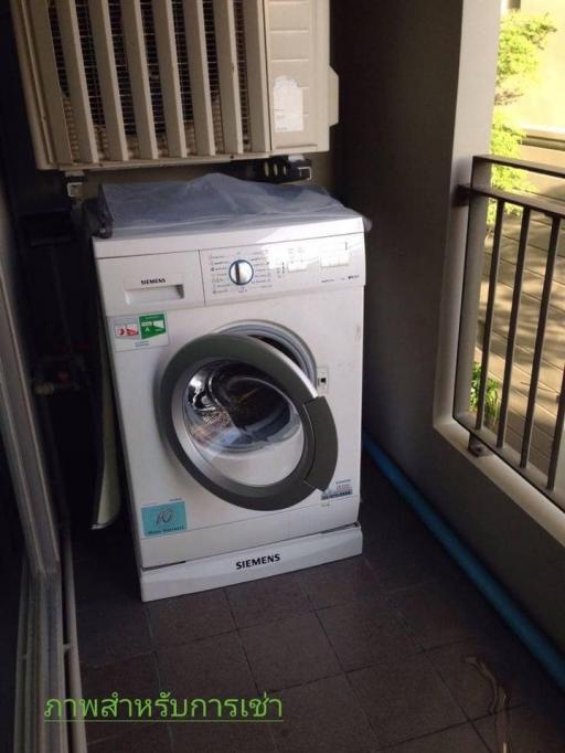 Front-loading Siemens washing machine in a utility area with air conditioner above