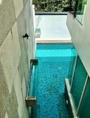 Private swimming pool with glass barrier and surrounded by high walls providing seclusion