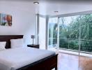Modern bedroom with large windows and a view of greenery