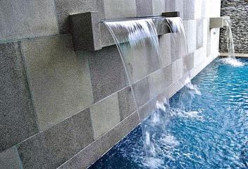Modern wall with water feature flowing into a pool