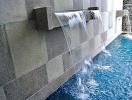 Modern wall with water feature flowing into a pool