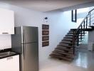 Modern kitchen with stainless steel refrigerator and wooden staircase
