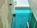 Narrow residential pool with glass barrier and stone wall