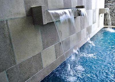 Modern pool with water feature and stone wall