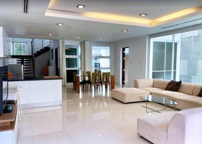 Spacious and modern open-plan living room with attached kitchen, ample natural light, and contemporary furnishings