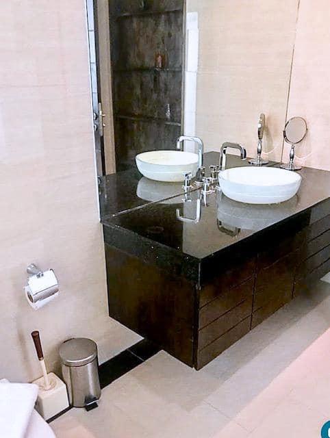 Modern bathroom with double vanity sinks, large mirror, and ample lighting