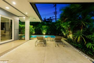 Spacious patio area with swimming pool and lounge chairs at dusk