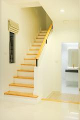 Brightly lit staircase with wooden steps leading towards upper level