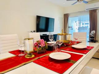 Elegant dining area with a modern white table set for a meal, adjacent to a comfortable living space