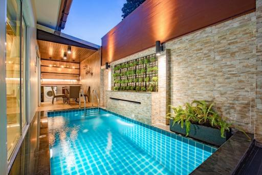 Modern home with an outdoor swimming pool, wall garden, and elegant lighting at dusk
