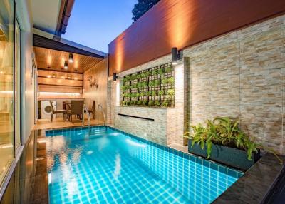Modern home with an outdoor swimming pool, wall garden, and elegant lighting at dusk
