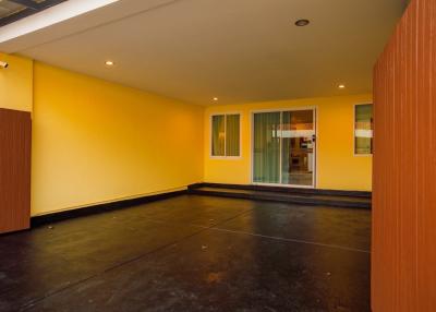 Spacious empty room with yellow walls, dark flooring and glass doors