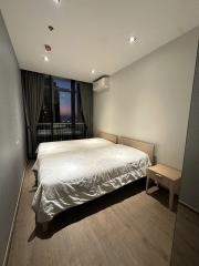 Cozy bedroom with double bed and city view at dusk