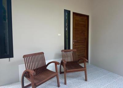 Two wooden chairs on a residential balcony with tiled flooring