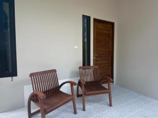 Two wooden chairs on a residential balcony with tiled flooring