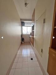 Narrow hallway with pink tiled flooring and wooden doors leading to different rooms